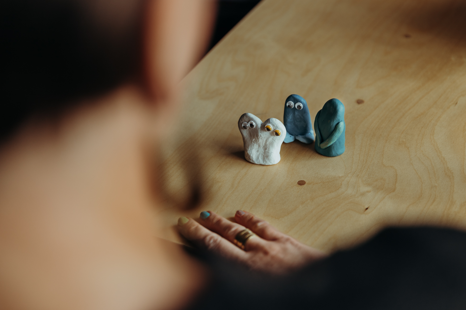 Drei Figuren stehen auf einem Tisch. Eine Person schaut auf die Figuren.